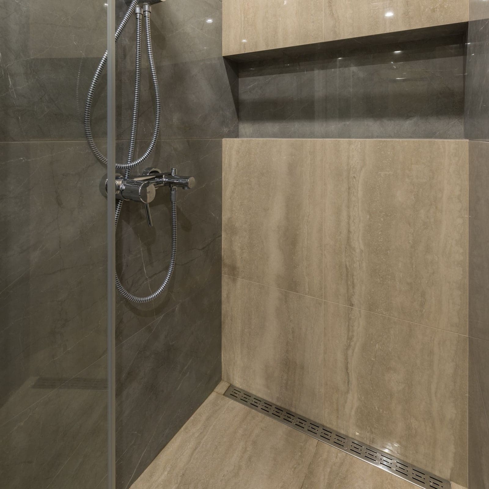 Coin d’une douche de plain-pied en grand format, caniveau aligné au pied du mur