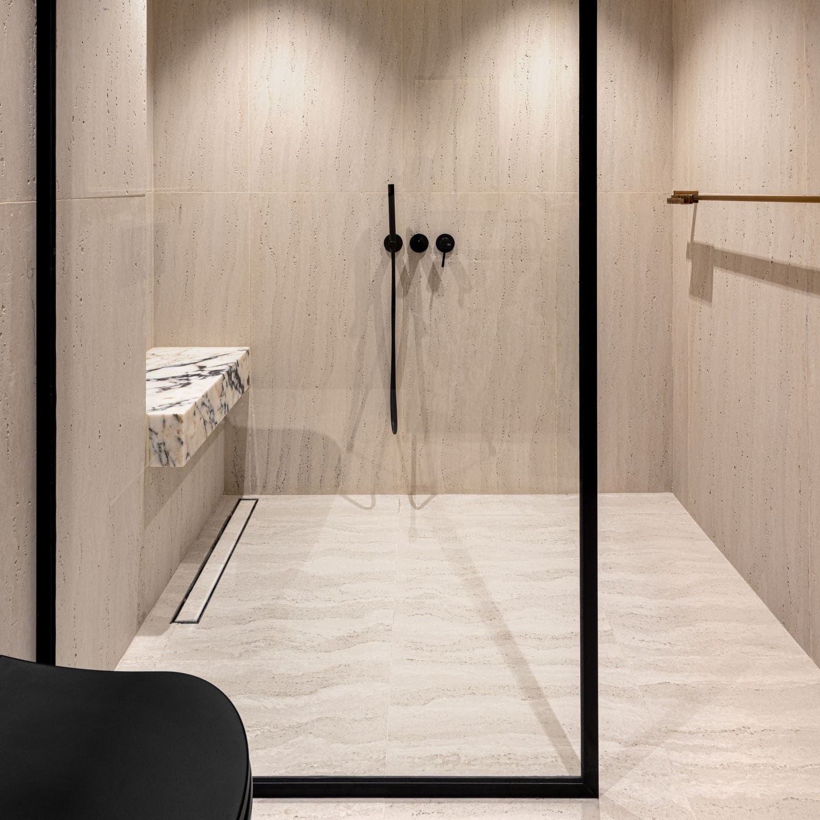 Douche de plain-pied en grès clair grand format, caniveau au pied du mur et paroi vitrée